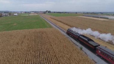 Strasburg, Pennsylvania, Ekim 2019 - Yenilenmiş bir N & W buhar makinesinin havadan görünüşü ve arkası ve manzarası, çiftlikte seyahat ederken antika yolcu arabalarını çekerken duman ve buhar üflüyor
