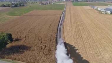 Bir buharlı trenin hava manzarası duman ve buhar üflüyor ve yukarıdan görüldüğü gibi kırsal bölgede ilerliyor.