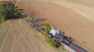 Strasburg, Pennsylvania, Ekim 2019 - Duman ve buhar üfleyen bir buhar treninin havadan görünüşü yukarıdan görüldüğü gibi kırsal alanda yavaşça ilerliyor