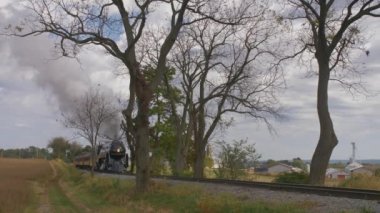 Strasburg, Pensilvanya, Ekim 2019 - Buharlı tren ağaçlar arasında yavaşça ilerlerken duman ve buhar üflüyor