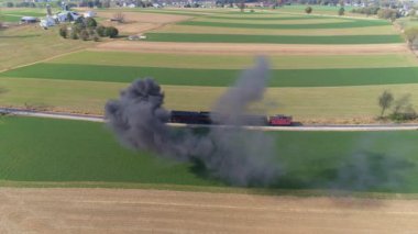 Strasburg 'da. Pensilvanya, Ekim 2019 - Buharlı lokomotifin havadan görünüşü, siyah duman ve buhar üflerken hala kırsalda duruyor