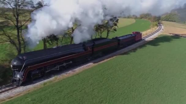 黒煙と蒸気を吹く田舎を旅するアンティークの復元された蒸気機関車の空中正面近くのビュー — ストック動画