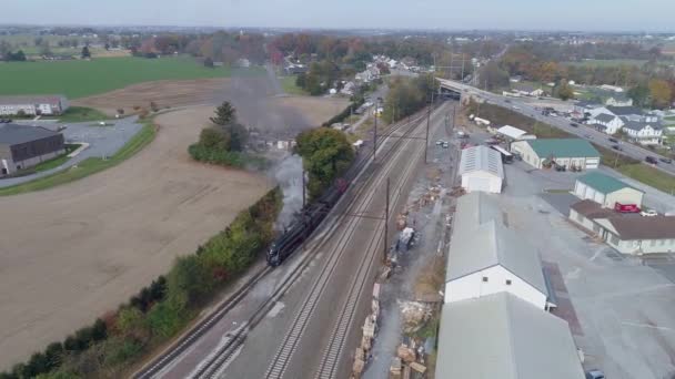 两列经过货场的复古蒸汽机车的空中俯瞰景象 然后随着它喷出黑烟和蒸汽而离开并穿过树木 — 图库视频影像