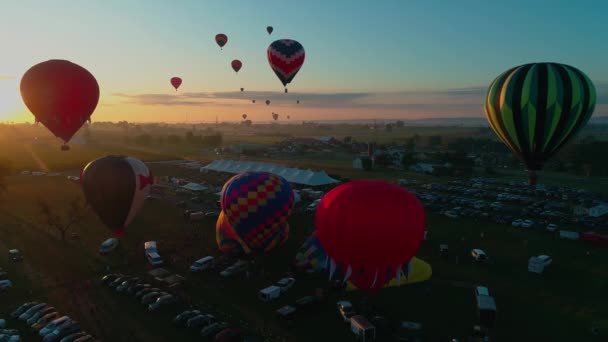 ペンシルベニア州の田舎で晴れた夏の日の祭りの間 早朝に複数の熱気球の空中ビューは太陽に離陸します — ストック動画