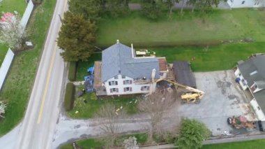 Eski bir çiftlik evinin çatısını eski aletlerle değiştiren Amish erkeklerinin hava görüntüsü.