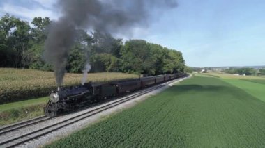 Güneşli bir yaz gününde istasyondan ayrılan Yolcu Arabalarıyla Antik Buharlı Motorun Uçuşunun Hava Görüntüsü