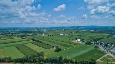 Yazın mavi gökyüzü ve beyaz kabarık bulutlarla tarlaların havadan görünüşü