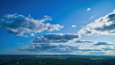 Mavi gökyüzü ve çoklu bulutlar bir ufuk ve gizli bir güneşi gösteriyor.