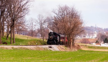 Buhar treni kış günü yolcu vagonlarını çekiyor.