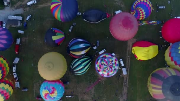 早朝の複数の熱気球の空中下の景色は ペンシルベニア州の田舎で晴れた夏の日の祭りの間に離陸する準備ができています — ストック動画