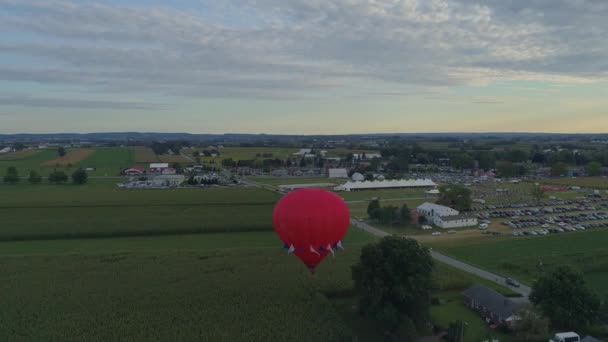 ペンシルベニア州の田舎で晴れた夏の日の祭りの間に農場のトウモロコシ作物に触れる熱気球の空中ビュー — ストック動画