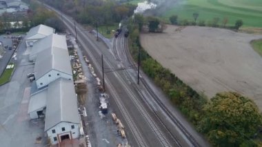 Beyaz duman ve buhar üflerken iki antika tamir edilmiş buharlı lokomotifin havadan görüntüsü.