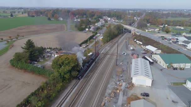 白い煙と蒸気を吹いている様子を眺めながら貨物ヤードを通って移動するアンティーク復元蒸気機関車の空中写真 — ストック動画