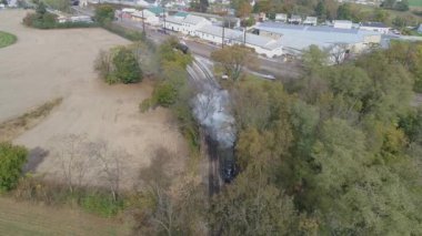 Antik iki lokomotifin tepeden görünüşü, buharlı lokomotifi tamir etti, nakliye sahasında seyahat ediyor, sonra siyah duman ve buhar üfleyerek ağaçların arasından ayrılıyor ve seyahat ediyor.