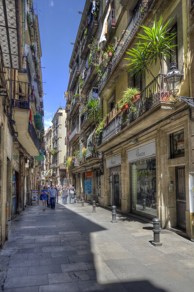 Barcelona, Spain - May 22, 2015: People walk in a narrow street with cafe's in the Gothic Quarter of downtown Barcelona, Spain on May 22, 2015.