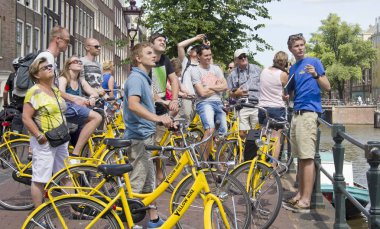 Turistler Amsterdam'da bisiklet üzerinde