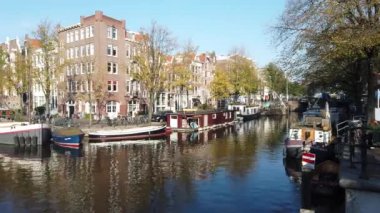 Amsterdam, Hollanda - 21 Ekim 2019: Amsterdam kanalında tarihi binalar ve Hollanda 'da sonbahar ağaçları olan tekneler 21 Ekim 2019