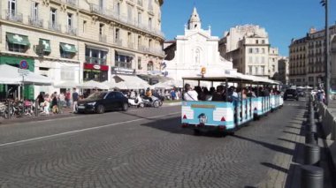 Yolcularla dolu turizm treni 27 Eylül 2019 'da Fransa' nın Marsilya limanındaki Quai des Belges boyunca yol alır.