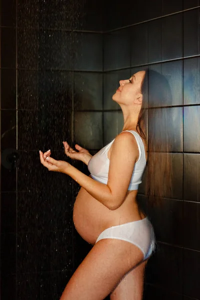 Ciężarna piękna kobieta w białym bikini pod prysznicem. Koncepcja zdrowego i szczęśliwego macierzyństwa. — Zdjęcie stockowe