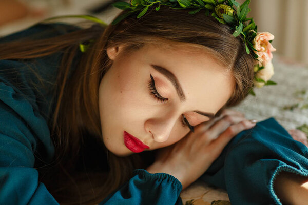 Крупный план портрета красивой молодой девушки в свежем цветочном венке на голове. Посмотри вниз. Концепция свежести, молодости и весны
