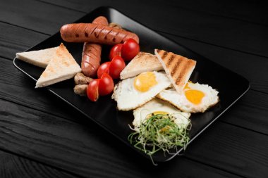 Siyah ahşap zemin üzerine İngiliz kahvaltısı ile plaka.