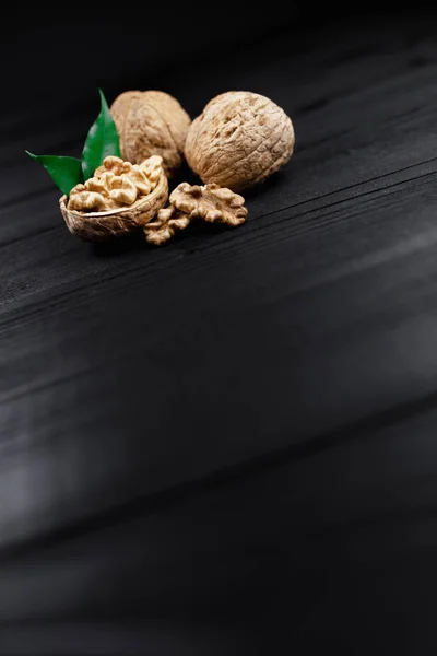 Nueces y nueces y nueces enteras sobre fondo rústico de madera negra . — Foto de Stock