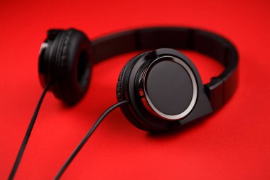 Kırmızı zemin üzerine siyah kulaklık. Müzik konsepti.
