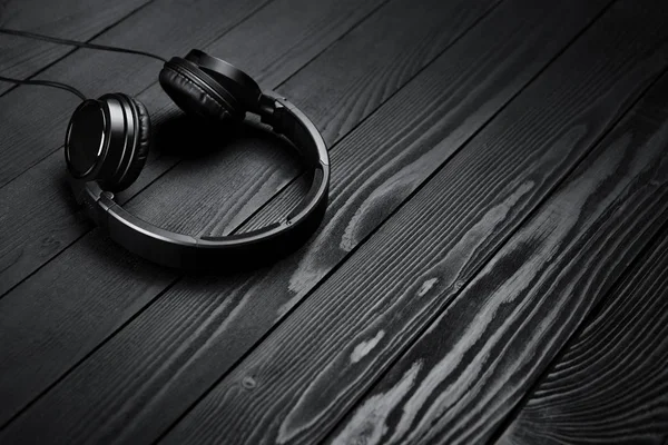 Auriculares negros sobre fondo oscuro de madera negra . — Foto de Stock