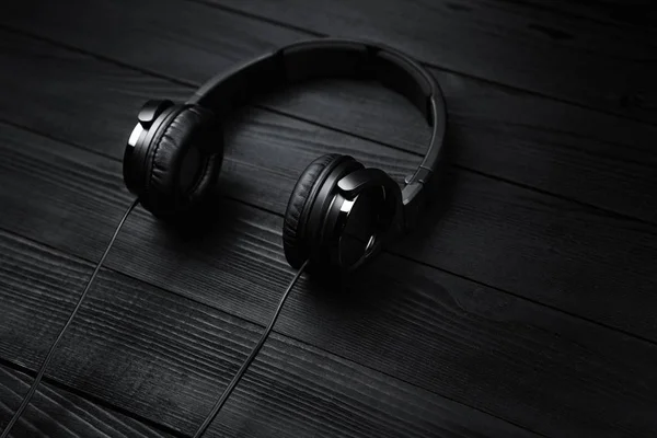 Auriculares negros sobre fondo oscuro de madera negra . —  Fotos de Stock