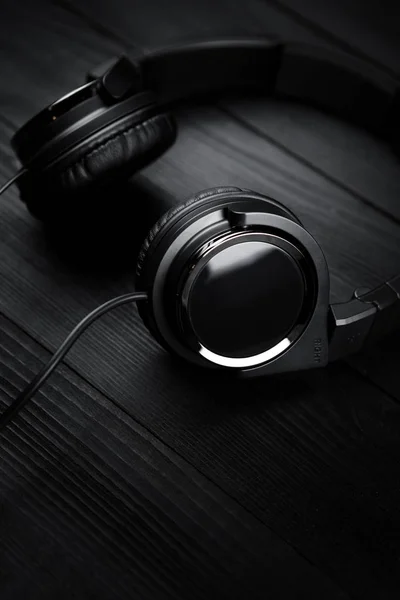 Black headphones on black wooden dark background. — Stock Photo, Image