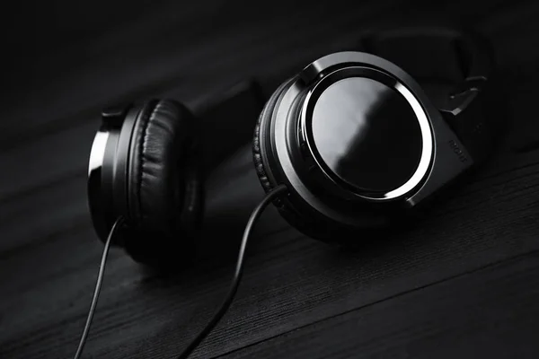 Fones de ouvido pretos em preto fundo escuro de madeira . — Fotografia de Stock