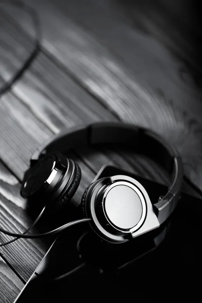 Tablet digital e fones de ouvido em uma mesa de madeira escura . — Fotografia de Stock