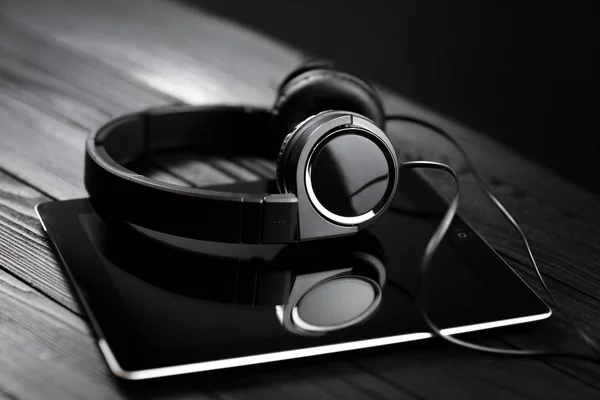 Digital tablet and headphones on a dark wooden table. — Stock Photo, Image