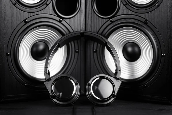 Photo of black music audio speaker and headphones. Close-up.