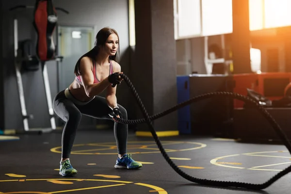 Atlética joven haciendo ejercicios crossfit con una cuerda . — Foto de Stock
