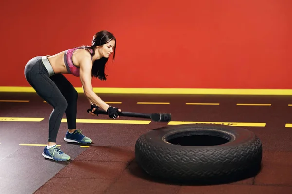 Fit jonge vrouw trainen in de fitnessruimte met hamer en trekker wiel. — Stockfoto