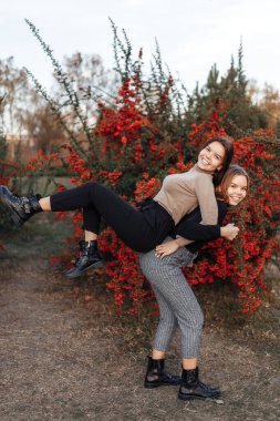 Neşeli gülüşlü, günlük kıyafetli iki genç ikiz kız kardeş parkta iyi eğlenceler. Aile kavramı.