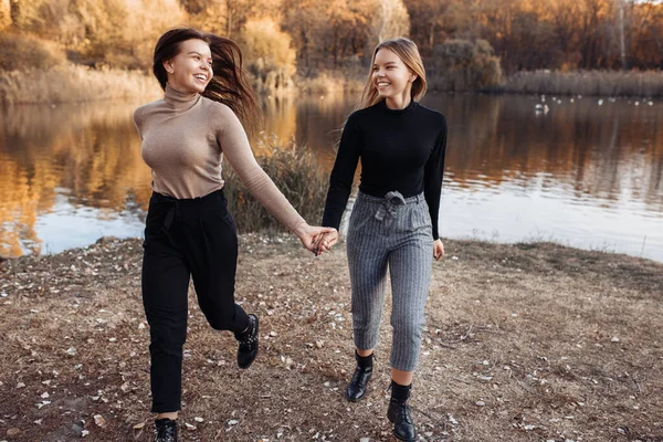 Neşeli, rahat giyimli, parlak gülümsemeli iki genç ikiz kız kardeş parkta iyi eğlenceler. Aile kavramı. — Stok fotoğraf
