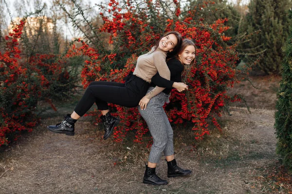 Beautiful two young twin sisters in casual outfit with bright smile have fun at the park. Family concept. — Stock Photo, Image