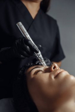 Cosmetologist make procedure for cleaning skin with steel tool from blackheads and acne in cosmetology center. clipart