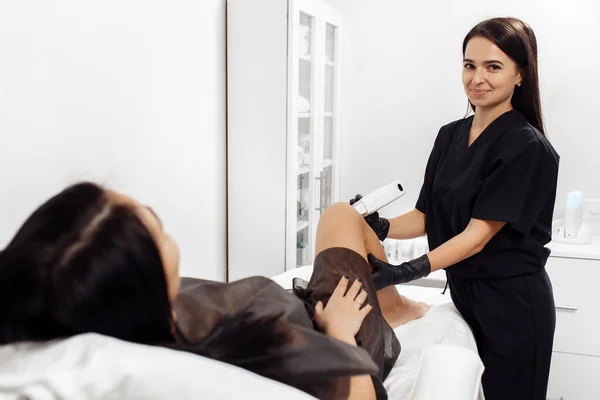 Cosmetologist faz o cabelo remover o procedimento na perna da mulher no armário cosmetology. — Fotografia de Stock
