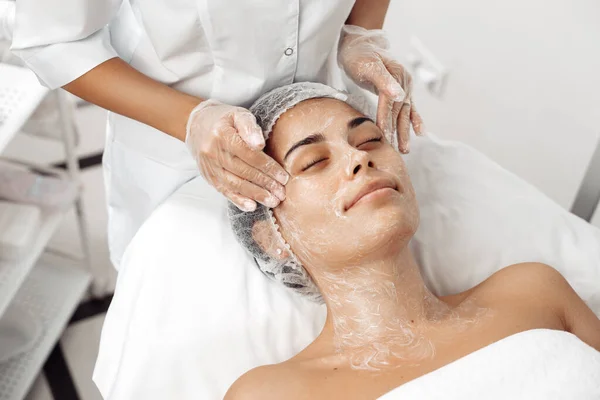 Cosmetólogo aplicar crema en la cara femenina en el salón de cosmetología . — Foto de Stock