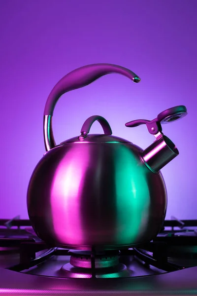 Close-up photo of stainless steel kettle in neon lights over purple background. — Stock Photo, Image