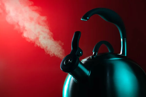 Photo of stainless steel kettle in neon light over red background. Steam from the kettle through the whistle. — Stock Photo, Image