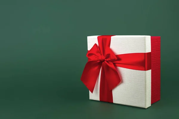 Aranyos minimalista karácsonyi ajándék doboz szalaggal elszigetelt zöld háttér. — Stock Fotó