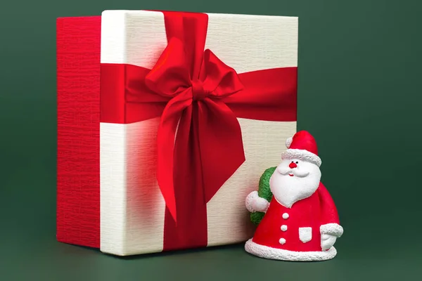 Nahaufnahme Foto von Gips bunten Weihnachtsmann vor Weihnachtsgeschenk-Box über grünem Hintergrund. — Stockfoto