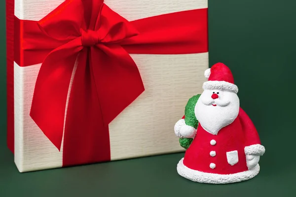 Nahaufnahme Foto von glücklichen Gips bunten Weihnachtsmann vor Weihnachtsgeschenk-Box über grünem Hintergrund. — Stockfoto