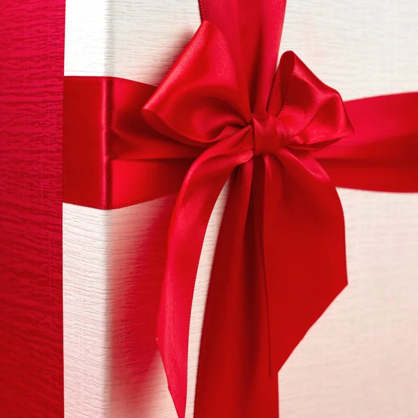 Elég minimalista karácsonyi ajándék doboz szalaggal elszigetelt piros háttér. — Stock Fotó