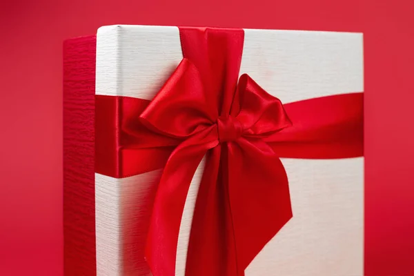 Ziemlich minimalistische Weihnachtsgeschenkschachtel mit Band isoliert über rotem Hintergrund. — Stockfoto