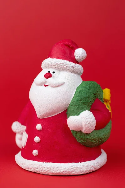 Ganzes Foto von niedlichen Gips bunten Weihnachtsmann isoliert über rotem Hintergrund. Neujahrs- und Weihnachtskonzept. — Stockfoto